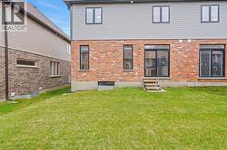 Expansive green lawn with a two-story exterior featuring a brick first level and horizontal siding on the second - 