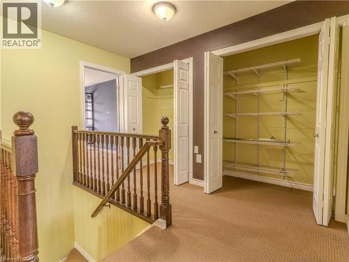 Hallway featuring carpeted flooring, decorative wood railings, and two closets with bi-fold doors and wire shelving - 338 Maverick Street, Waterloo, ON - Indoor Photo Showing Other Room