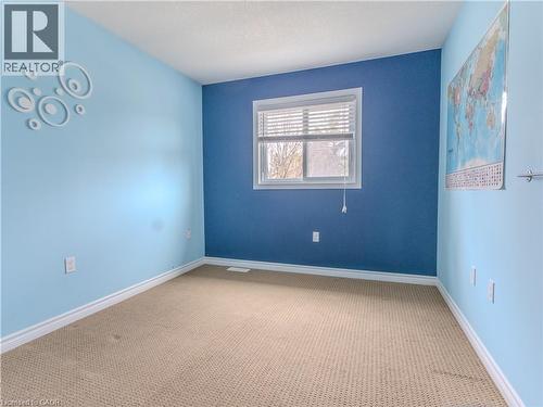 The room features a window with blinds, carpeted flooring, and light blue walls with a contrasting darker blue accent wall - 338 Maverick Street, Waterloo, ON - Indoor Photo Showing Other Room