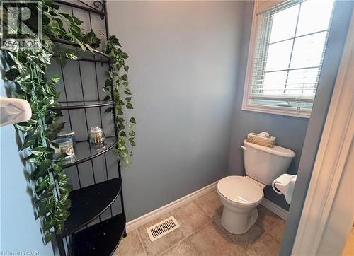 This powder room features neutral-toned floor tiles, a window with blinds, and a corner shelving unit - 338 Maverick Street, Waterloo, ON - Indoor Photo Showing Bathroom