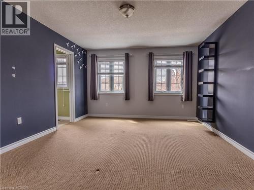 The room features two windows with blinds and curtains, a built-in shelving unit, and carpet flooring - 338 Maverick Street, Waterloo, ON - Indoor Photo Showing Other Room
