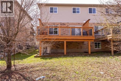 The property features a spacious wooden deck with dark railings, accessed by sliding glass doors, and a ground-level area with a lawn and trees - 338 Maverick Street, Waterloo, ON - Outdoor With Deck Patio Veranda