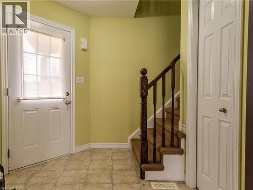 Entryway featuring tiled flooring, a white paneled door with window, and a carpeted staircase with a dark wood banister - 338 Maverick Street, Waterloo, ON - Indoor Photo Showing Other Room
