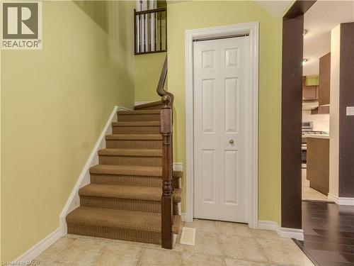 Entryway featuring tiled flooring, a carpeted staircase with a wooden handrail, and a white paneled door - 338 Maverick Street, Waterloo, ON - Indoor Photo Showing Other Room