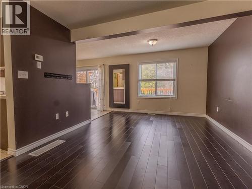 This room features dark hardwood flooring, light-colored walls with accent walls in a darker shade, and a window providing natural light - 338 Maverick Street, Waterloo, ON - Indoor Photo Showing Other Room