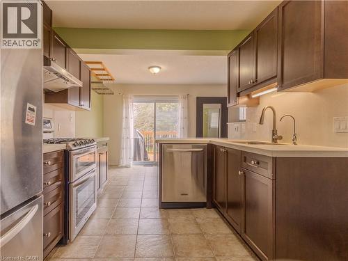 The kitchen features stainless steel appliances, dark wood cabinetry, and tiled flooring - 338 Maverick Street, Waterloo, ON - Indoor Photo Showing Kitchen