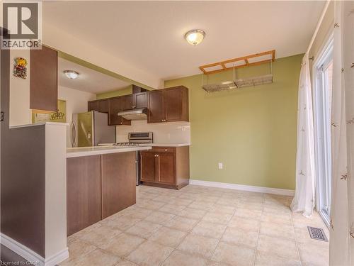 The kitchen features wood cabinetry, stainless steel appliances, and a tiled floor - 338 Maverick Street, Waterloo, ON - Indoor Photo Showing Kitchen
