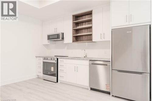 Kitchen featuring white cabinetry, stainless steel appliances including a refrigerator, range, microwave, and dishwasher, and light-colored countertops - 144 Everett Common, St. Catharines, ON - Indoor Photo Showing Kitchen