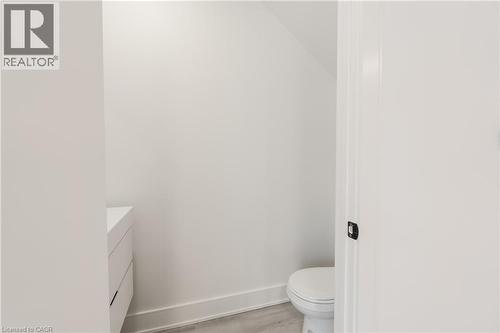 This powder room features a modern white vanity and a toilet, set against light-colored walls - 144 Everett Common, St. Catharines, ON - Indoor Photo Showing Bathroom