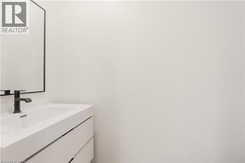 Bathroom vanity featuring a white rectangular sink, a black faucet, and a mirror with a black frame - 144 Everett Common, St. Catharines, ON - Indoor Photo Showing Bathroom