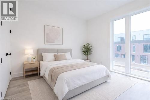 Bedroom featuring light-toned flooring, a large window providing natural light, and a light-colored area rug - 144 Everett Common, St. Catharines, ON - Indoor Photo Showing Bedroom