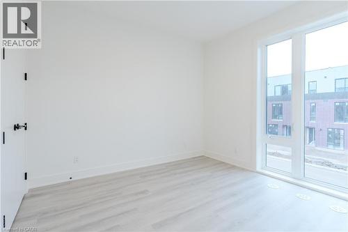 Well-lit room featuring light-toned flooring, white walls, and a large window - 144 Everett Common, St. Catharines, ON - Indoor Photo Showing Other Room