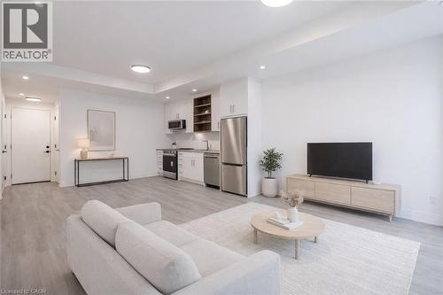 Open concept living area featuring light-toned flooring, recessed lighting, and a kitchen with stainless steel appliances - 144 Everett Common, St. Catharines, ON - Indoor Photo Showing Living Room