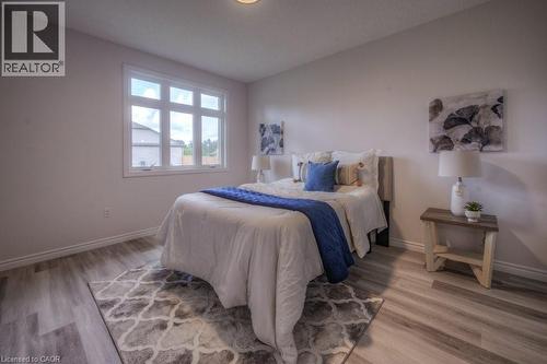 Bright room featuring wood-finish flooring, a large multi-pane window, white baseboards, and a neutral wall color - 48 Main Street E, Innerkip, ON - Indoor Photo Showing Bedroom