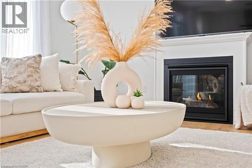 Detailed view of a glass covered fireplace and wood finished floors - 66 Cesar Place, Ancaster, ON - Indoor Photo Showing Living Room With Fireplace