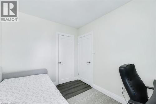 Bright room featuring two white panel doors with brushed nickel hardware, wood-finish flooring, and crisp white baseboards - 18 Tweedsmuir Avenue, London, ON - Indoor Photo Showing Bedroom