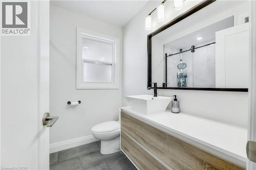 Modern bathroom featuring a wood-finish vanity with a white countertop and vessel sink - 18 Tweedsmuir Avenue, London, ON - Indoor Photo Showing Bathroom