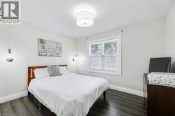 Bedroom featuring wood-finish flooring, white baseboards, and light-toned walls - 