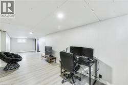 Spacious room featuring light wood-finish flooring, white paneled walls, recessed lighting, and a white ceiling - 