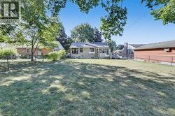 Expansive grassy yard with mature trees providing partial shade - 