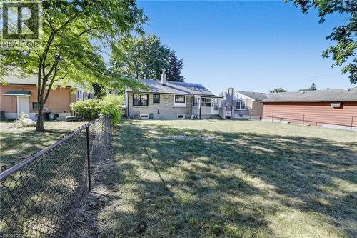Expansive backyard featuring a chain-link fence, mature trees, and a brick exterior home with multiple windows - 18 Tweedsmuir Avenue, London, ON - Outdoor