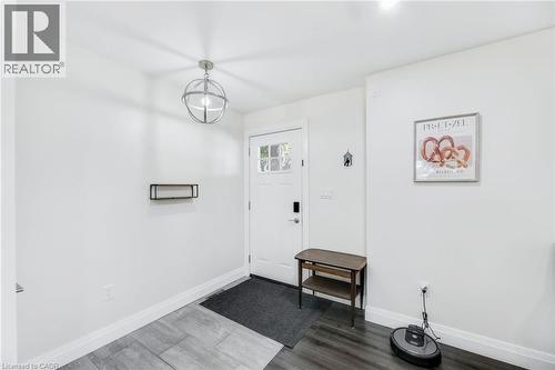 Entryway featuring a white paneled door with glass inserts, a contemporary spherical pendant light, and two-tone wood-finish flooring - 18 Tweedsmuir Avenue, London, ON - Indoor Photo Showing Other Room