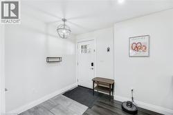 Entryway featuring a white paneled door with glass inserts, a contemporary spherical pendant light, and two-tone wood-finish flooring - 