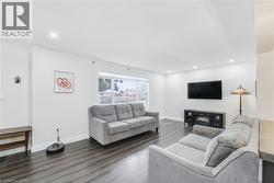 Spacious living area featuring wood-finish flooring, recessed lighting, a large window, and a media console with an electric fireplace - 