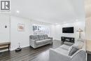 Spacious living area featuring wood-finish flooring, recessed lighting, a large window, and a media console with an electric fireplace - 18 Tweedsmuir Avenue, London, ON  - Indoor Photo Showing Living Room With Fireplace 