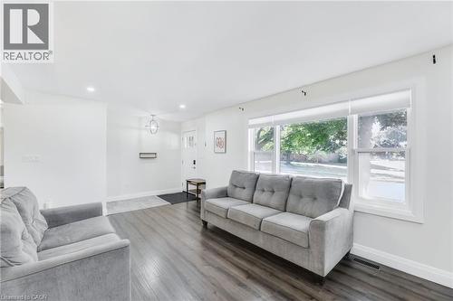 Bright living area featuring wood-finish flooring, recessed lighting, and a large front window with roller shades - 18 Tweedsmuir Avenue, London, ON - Indoor Photo Showing Living Room