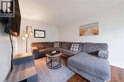 Living area featuring wood-finish flooring, white walls, and a recessed ceiling - 