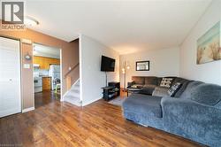 Living area featuring wood-finish flooring, a neutral color palette, and a carpeted staircase - 