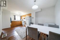 Open-concept kitchen and dining area featuring wood-finish flooring, ample cabinetry, a double window above the sink, and ceiling-mounted lighting - 