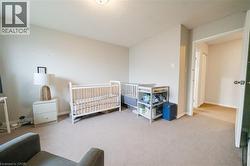 Spacious room featuring neutral carpeting, light-toned walls, and an open doorway revealing an interior hallway with wood-finish flooring - 