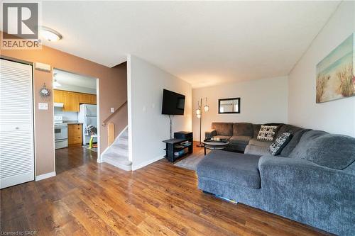 Living area featuring wood-finish flooring, a neutral color palette, and a carpeted staircase - 391 Pioneer Drive Unit# 4, Kitchener, ON - Indoor Photo Showing Living Room