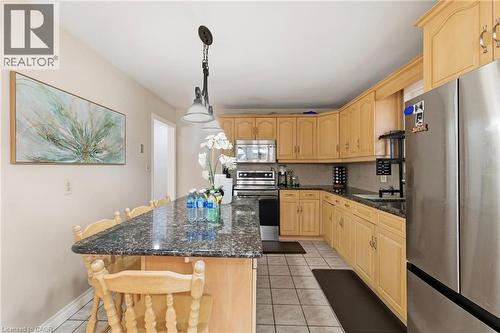 Kitchen featuring appliances with stainless steel finishes, dark stone countertops, a kitchen breakfast bar, and hanging light fixtures - 364 Roselawn Place, Waterloo, ON - Indoor Photo Showing Kitchen