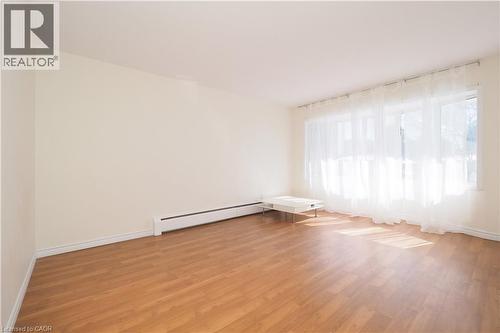 Spacious interior featuring expansive windows, wood-finish flooring, light-toned walls, and white baseboards - 24 Austin Drive Unit# 3, Waterloo, ON - Indoor Photo Showing Other Room
