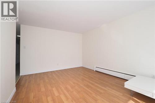 Spacious room with wood-finish flooring, white baseboards, and neutral wall paint - 24 Austin Drive Unit# 3, Waterloo, ON - Indoor Photo Showing Other Room