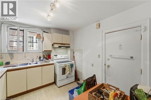 Kitchen featuring a dual-basin stainless steel sink, white ceramic tile backsplash, and light-toned cabinetry - 509 Aberdeen Avenue, Hamilton, ON - Indoor Photo Showing Kitchen With Double Sink