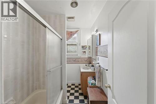 Bathroom featuring a tub/shower combination with sliding glass doors, white tiled walls, and a checkerboard floor - 509 Aberdeen Avenue, Hamilton, ON - Indoor Photo Showing Bathroom