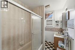 Bathroom featuring a tiled shower with sliding glass doors, a vanity with a built-in sink, a wall-mounted medicine cabinet, and checkerboard floor tiles - 