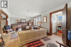 Living space featuring wood-finish flooring, a brick fireplace, white trim, wood door frames, and multi-pane windows - 