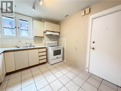 Kitchen featuring white appliances, a double basin sink, ample cabinetry, and tile flooring - 509 Aberdeen Avenue, Hamilton, ON - Indoor Photo Showing Kitchen With Double Sink