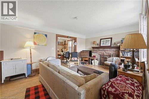 Living room featuring wood-finish flooring, a brick fireplace with a wood mantel, and broad baseboards - 509 Aberdeen Avenue, Hamilton, ON - Indoor Photo Showing Living Room With Fireplace