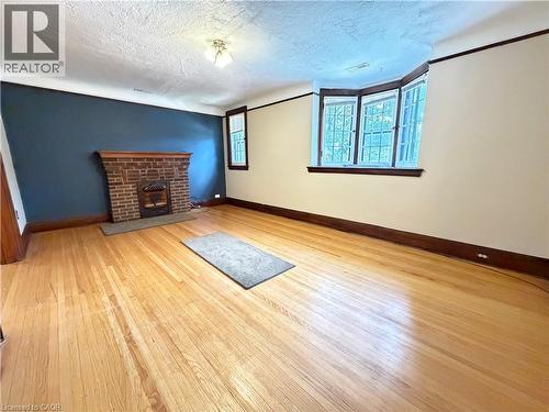 Hardwood flooring throughout featuring a brick fireplace with a detailed wood mantel - 509 Aberdeen Avenue, Hamilton, ON - Indoor With Fireplace