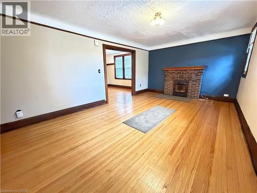 Spacious living area featuring wood-finish flooring, a brick-front fireplace, and dark-stained wood trim - 509 Aberdeen Avenue, Hamilton, ON - Indoor With Fireplace
