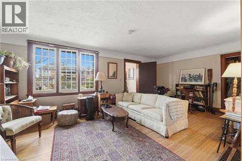 Living area featuring wood-finish flooring, a neutral wall palette, and three large windows with grid muntins - 509 Aberdeen Avenue, Hamilton, ON - Indoor Photo Showing Living Room