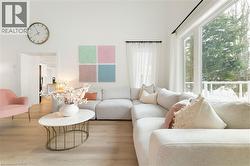 Spacious living area featuring high vaulted ceilings, large picture windows, wood-finish flooring, and a contemporary open concept design - 