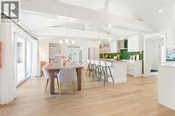 Open-concept living space featuring wood-finish flooring, vaulted ceilings with exposed beams, and sliding glass doors - 