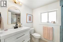 Modern bathroom featuring a white vanity with integrated sink, matte black faucet, and an arched gold-framed mirror - 
